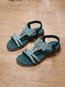 Close-up of bohemian flat sandals with sparkling blue rhinestone flower patterns