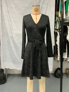 Detail view of black V-neck wrap dress with sequined pattern and bow waist