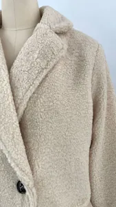 Detailed close-up view of a warm beige teddy fleece jacket with a classic lapel collar