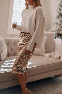 Sparkly gold sequin bodycon skirt styled with a cozy white sweater in a festive room.