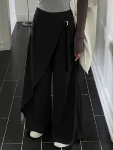 High-waisted black wide-leg trousers with asymmetrical wrap design and ring buckle.