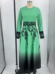 Dettaglio di un abito lungo verde a girocollo con stampa floreale nera e fondo sfumato.