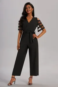 Elegante tuta nera con scollo a V e maniche con strisce in rete trasparente