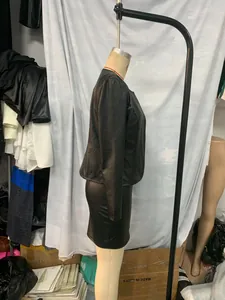 Side view of trendy black faux leather long sleeve jacket and mini skirt set on mannequin