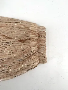 Close-up of sparkling rose gold sequined fabric and elasticized gathered cuff detail