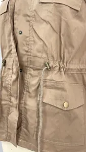 Détail rapproché d'une veste utilitaire kaki avec cordon de serrage et poche boutonnée