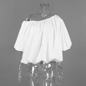 Close-up detail of a white asymmetric off-shoulder cotton blouse with elegant puff sleeves