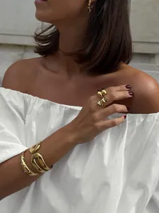 Detail view of a chic white asymmetric off-the-shoulder cotton blouse on a model
