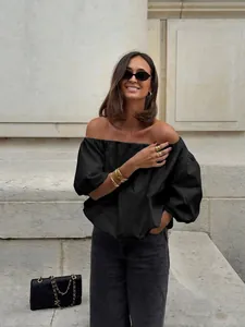Detailed view of off-the-shoulder cotton top with balloon sleeves worn by model.