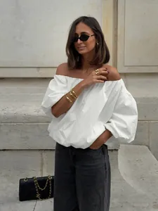 Detail view of stylish white off-the-shoulder cotton blouse with asymmetric design