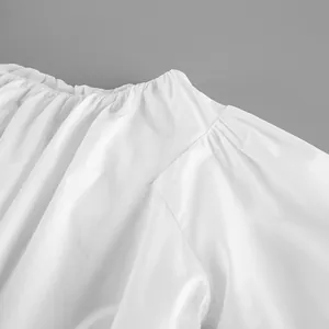 Close-up view of neckline pleats and fabric texture on white off-shoulder cotton blouse top