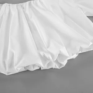 Detailed macro view of white cotton off-shoulder top showing pleated fabric texture.