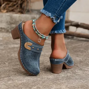 Detail of vintage carved blue chunky heel mules showing intricate floral patterns