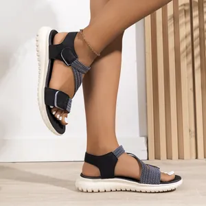 Detail of women's black wedge sandals with woven straps and velcro closure