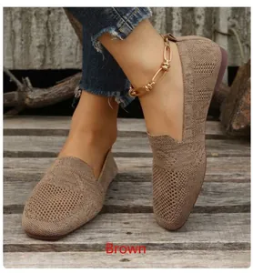 Close-up of brown fly-woven flat shoes with breathable mesh texture on wooden surface