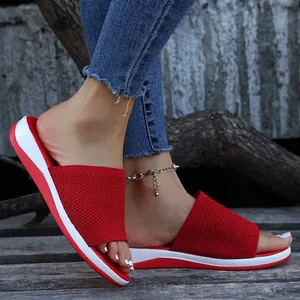 Close-up of red knitted breathable flat slippers for women in a rustic setting