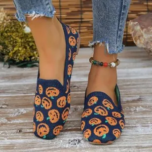 Detail of fly-knit women's loafers featuring orange pumpkin pattern on navy blue