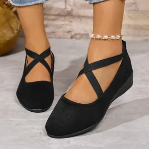 Dettaglio di scarpe con zeppa nere a punta tonda con elastici incrociati sul collo