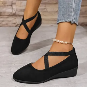 Dettaglio scarpe con zeppa nere a punta tonda con cinturini elastici incrociati.