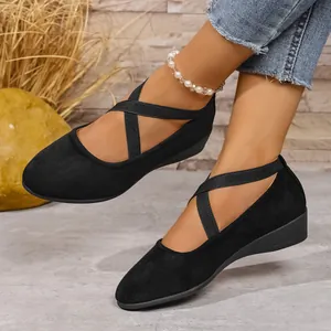 Primo piano di ballerine con zeppa in camoscio nero e cinturini incrociati su modella