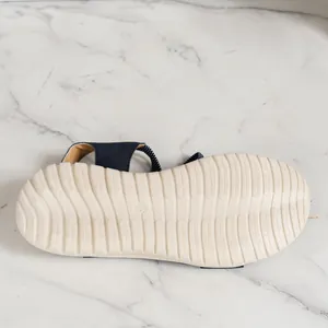 Detailed macro view of the anti-slip textured rubber sole on a navy blue wedge sandal