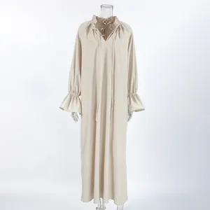 Macro view of French style V-neck linen dress with ruffled collar and tie detail
