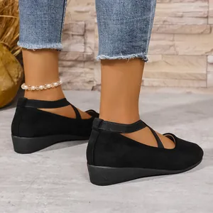 Dettaglio di scarpe con zeppa nere in finto scamosciato con cinturini incrociati