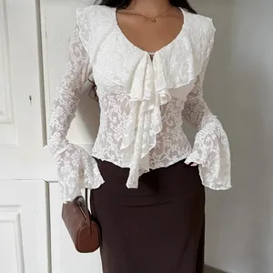 Dettaglio di camicia in pizzo bianco stile francese con volant e maniche a campana eleganti.