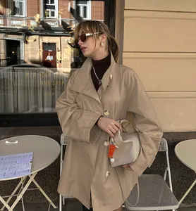 Elegant beige mid-length oversized trench coat for women worn in a cafe setting.