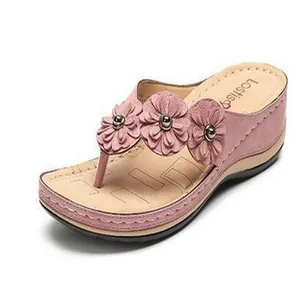 Dettaglio di sandalo rosa con zeppa e tre decorazioni floreali con suola imbottita