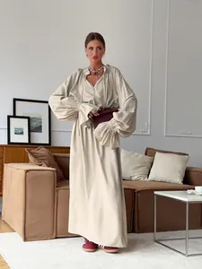 Elegantly styled beige linen maxi dress with ruffled sleeves shown in a home setting