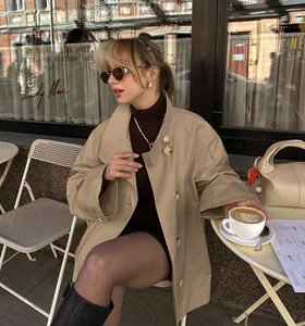 Stylish mid-length beige trench coat for women in a chic outdoor cafe setting