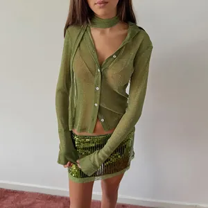 Close-up detail of a sparkling green long sleeve shirt with neck scarf and sequins