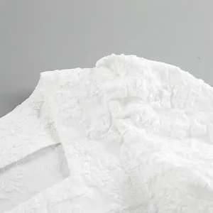 Dettaglio ravvicinato del tessuto jacquard bianco goffrato su una camicia retrò a collo quadrato