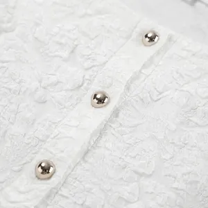 Dettaglio del tessuto jacquard bianco a rilievo con bottoni in argento lucido.