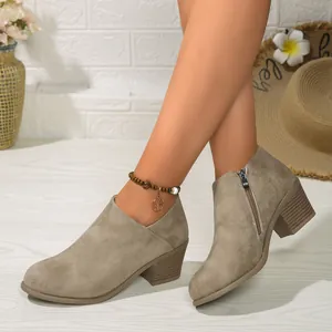 Detail view of khaki suede ankle boots with block heels and side zipper closure.