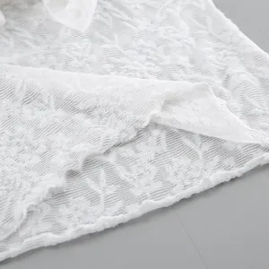 Vista macro che mostra la delicata trama del pizzo floreale bianco di una camicia