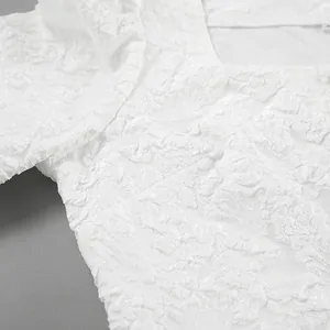 Dettaglio del tessuto jacquard floreale a rilievo bianco di una camicetta con maniche a sbuffo