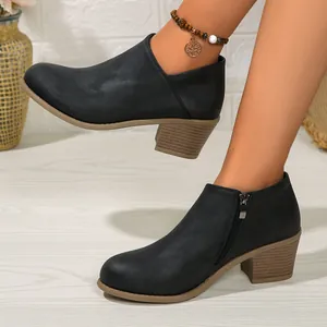 Detail of black matte ankle boots with stacked block heel and side zipper closure.