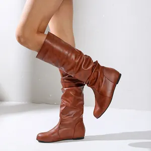 Stylish brown slouchy mid-calf flat boots featuring a round toe design on a model's legs