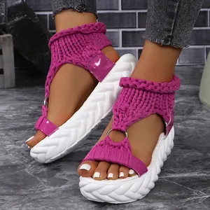 Close-up of purple knitted platform sandals with wavy white sole on model feet.