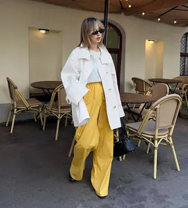 Full detail view of white oversized trench coat paired with vibrant yellow pants