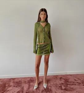 Close-up detail of olive green sheer shirt with neck tie and green sequin mini skirt