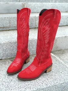 Detail of red suede cowboy boots with intricate white embroidery and stylish V-cut top
