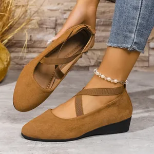 Dettaglio scarpe con zeppa in camoscio marrone con cinturini elastici incrociati e suola nera