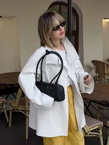 Chic oversized white mid-length trench coat for women captured in an outdoor cafe scene.
