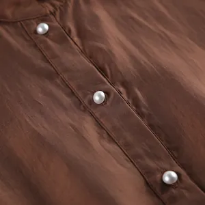Primer plano detallado de una blusa de Tencel marrón con elegantes botones de perlas