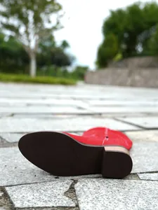 Close-up detail of the durable dark brown rubber sole on a red embroidered knight boot.