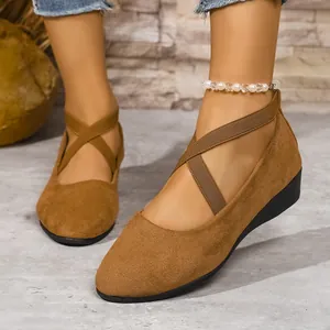 Primo piano di scarpe con zeppa in camoscio marrone con cinturini incrociati su piedi