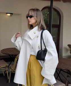 Lifestyle shot of a stylish white oversized trench coat for women in an outdoor cafe setting